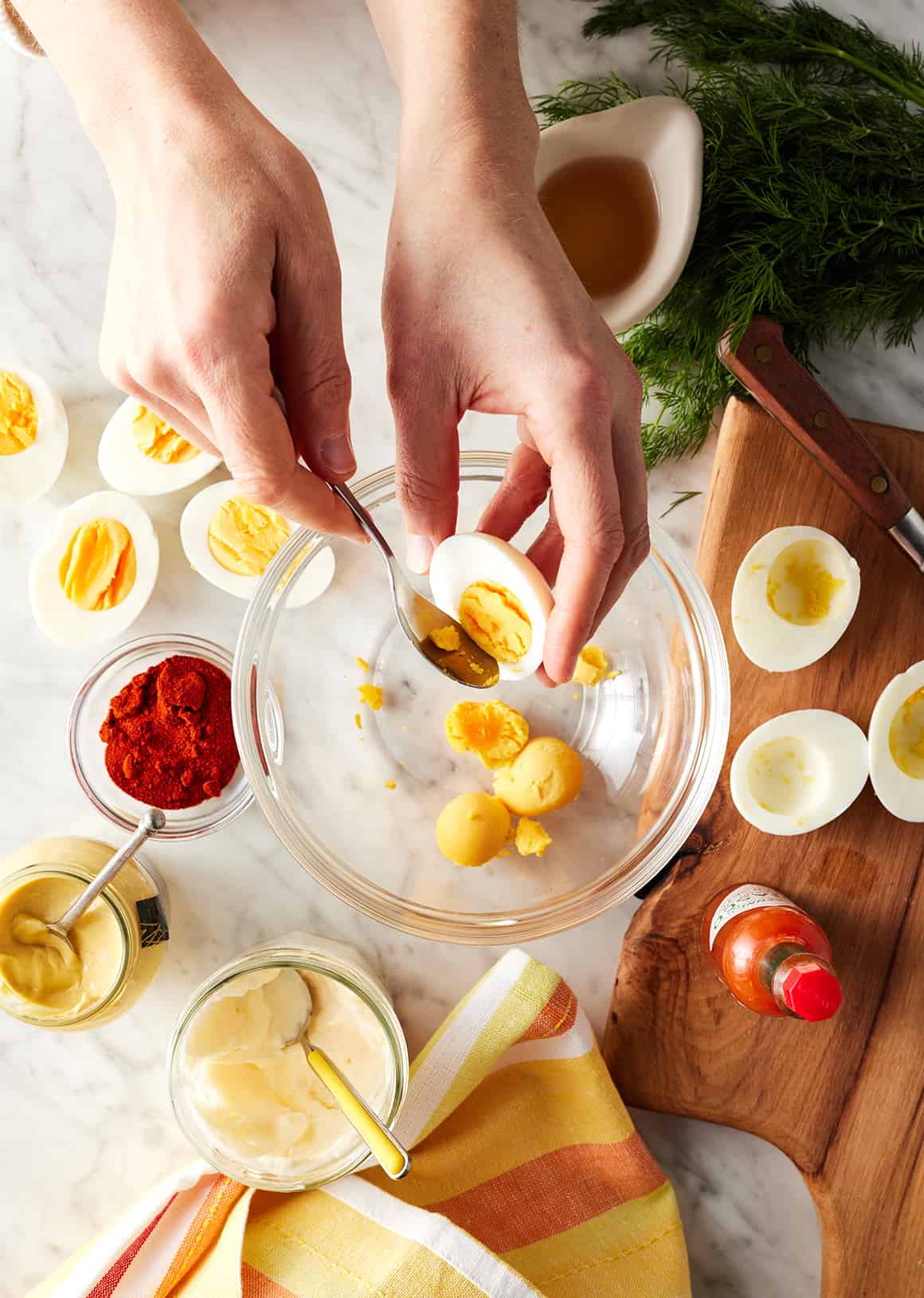 Scooping hard boiled egg yolks out of whites and into glass bowl